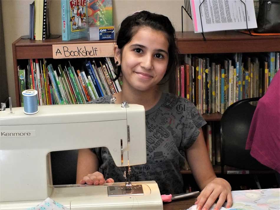 A young woman smiles at the camera during one of Lighting the Path's sewing lessons as a part of the Giving Hope Project